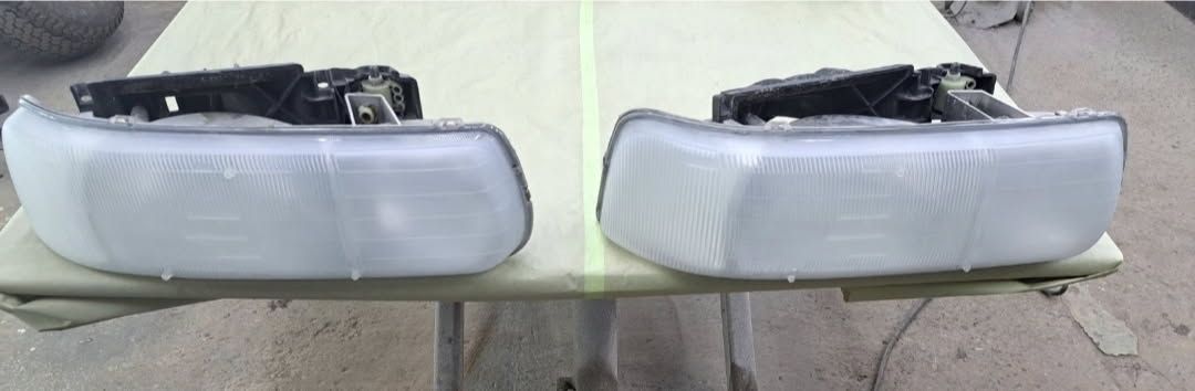 A magenta pickup truck with a black camper shell parked on an asphalt street in front of a building.