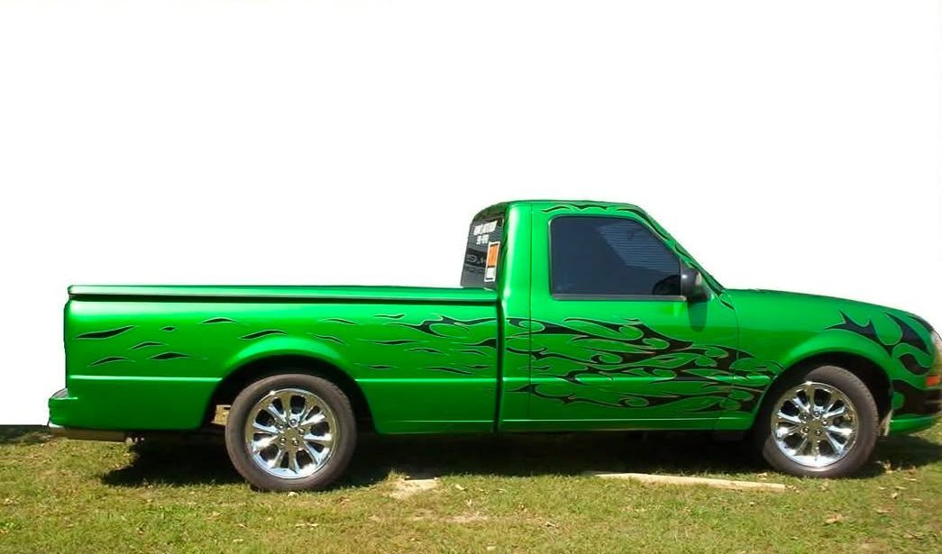 Green pickup truck with black detailing on chrome wheels, parked on grass.