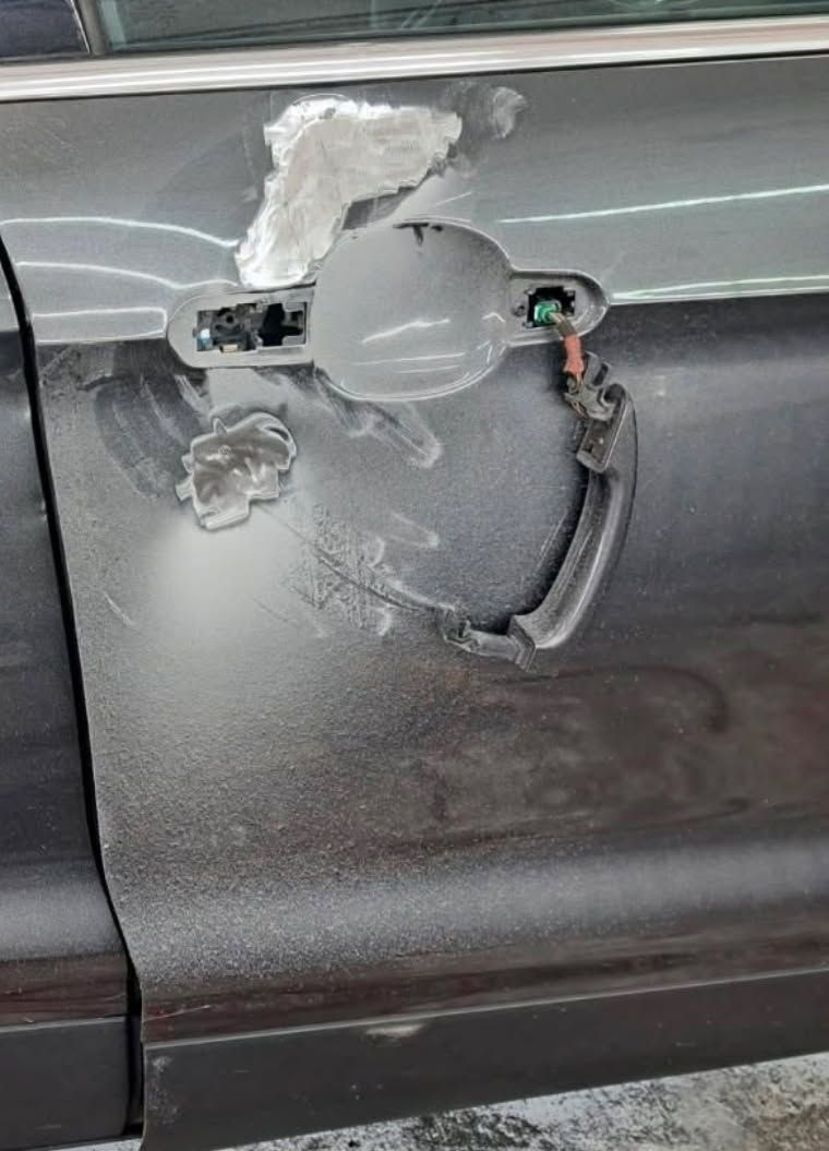 Damaged gray car door handle with broken trim and exposed wiring