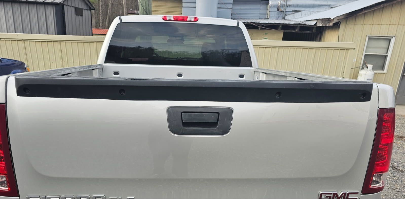 Rear view of a white GMC pickup truck with a black tailgate handle and red taillights