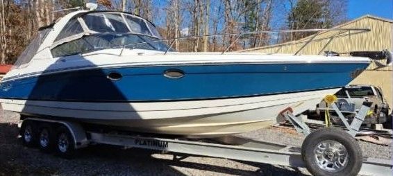 White and blue motorboat on a trailer, under a sunny sky.