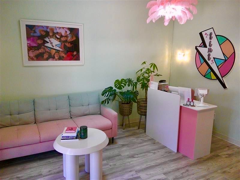 Modern pastel living room with pink sofa, white table, plant, and colorful wall art