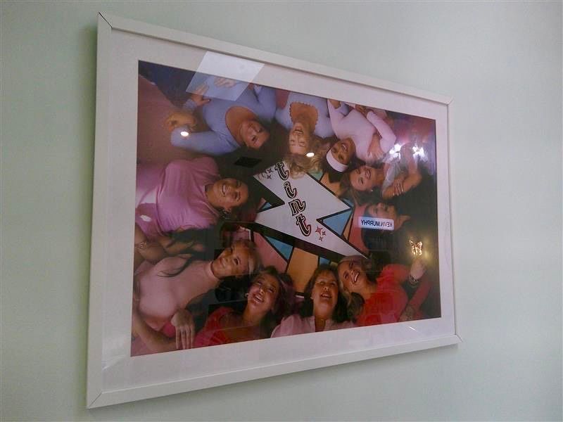 Framed photo of a smiling group posing around a star-shaped sign on a wall.