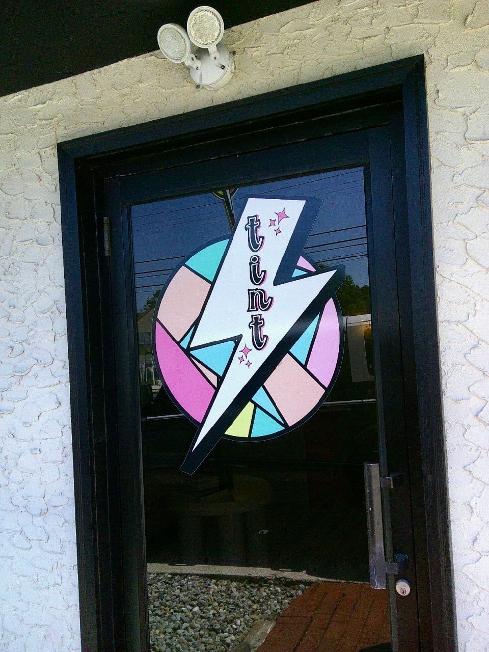 Storefront door with a colorful lightning-bolt logo and vertical lettering on the window.