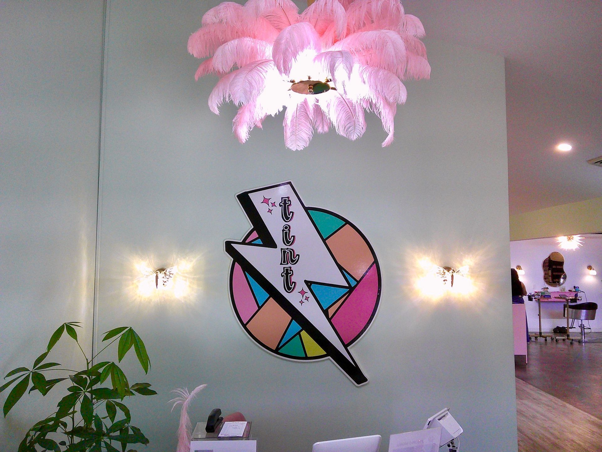 Colorful wall logo with lightning bolt in a bright lobby, accented by pink floral ceiling lights