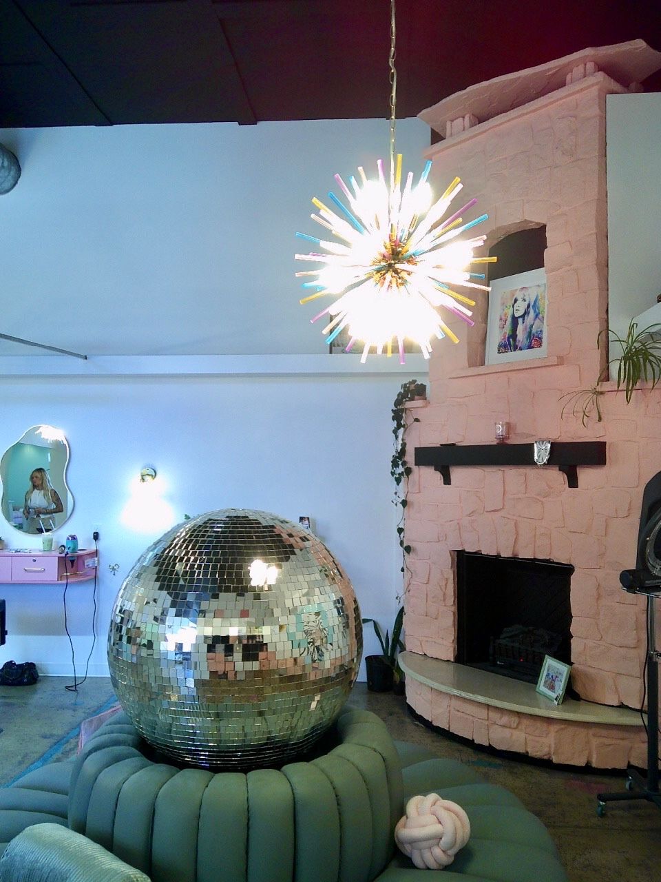 Living room with a mirrored disco ball, glowing starburst light, and fireplace mantel under a curved ceiling.
