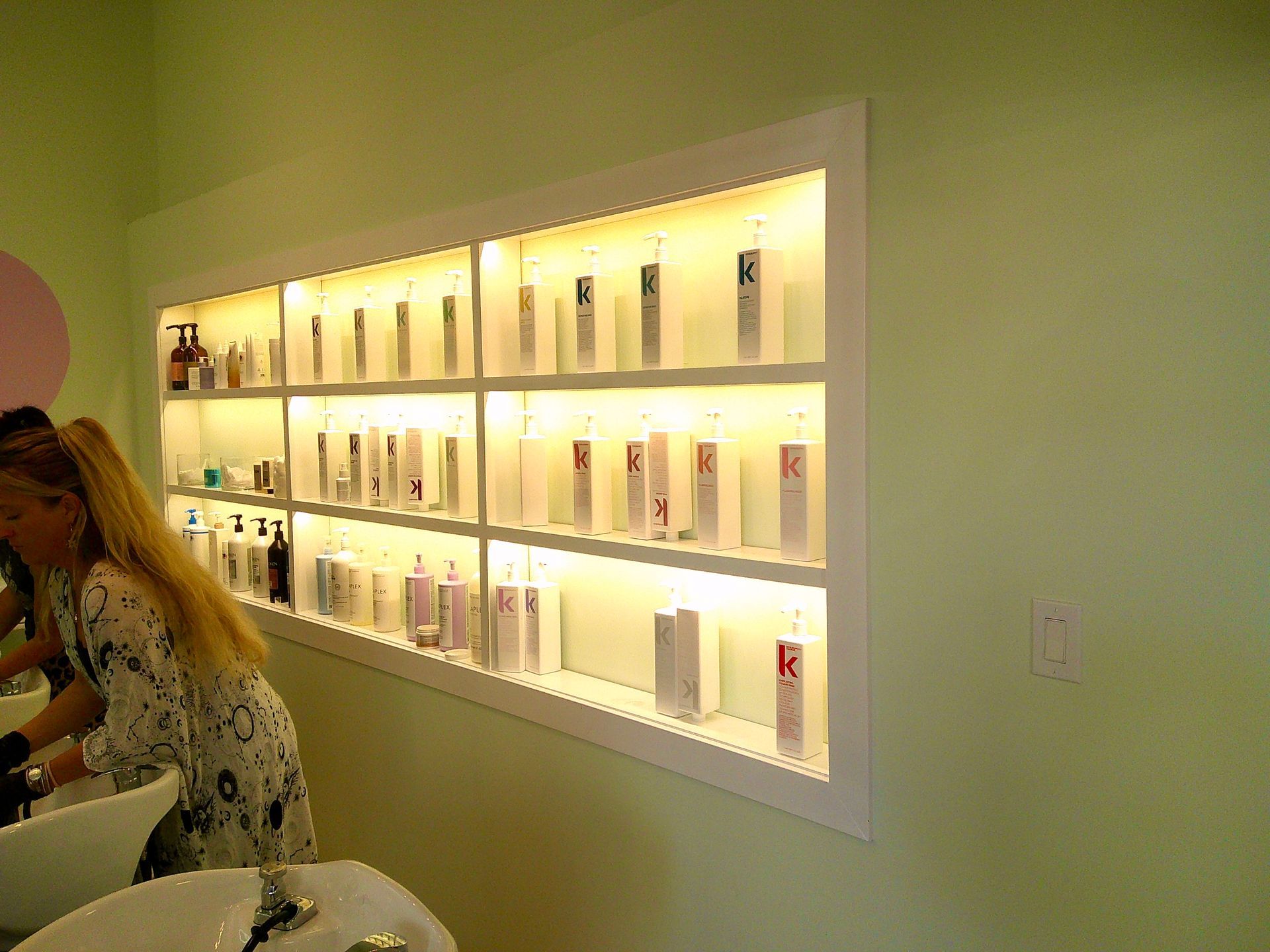 Backlit wall display of small product bottles and boxes in a boutique shop