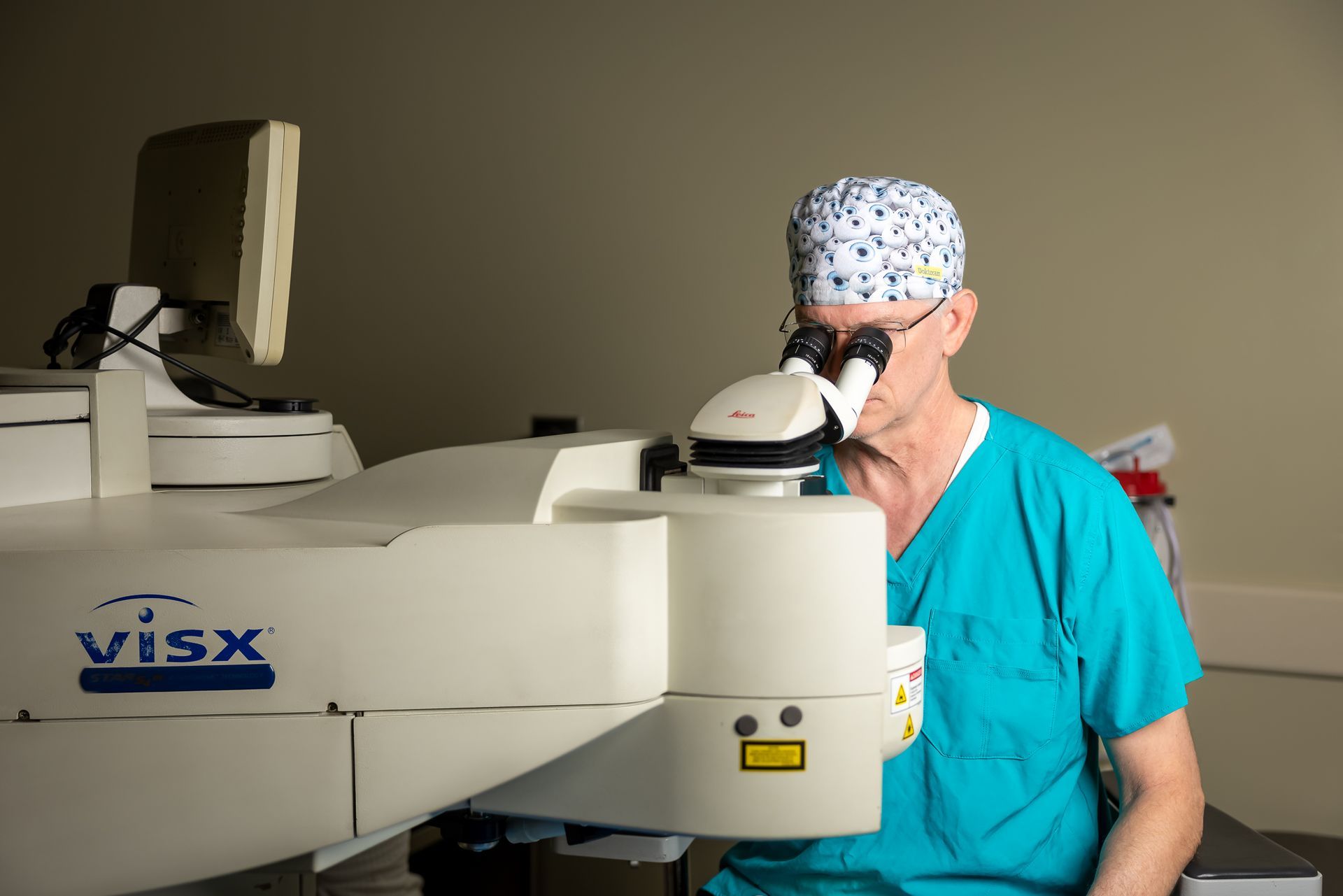 A person in a surgical gown is getting their eyes examined by a doctor