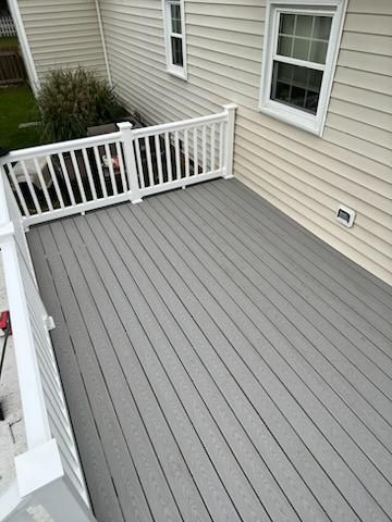 Gray composite deck with white railing next to a light-colored house.