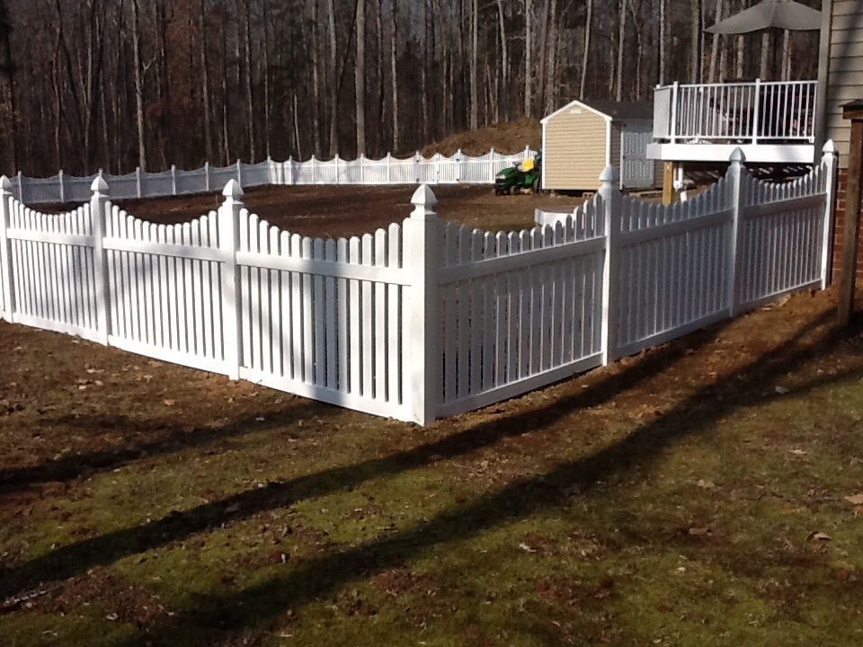White picket fence encloses a backyard with a shed and lawn.