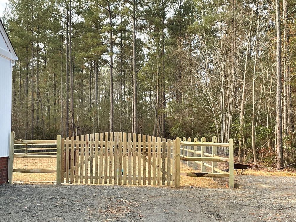 Wooden fence with gate leading to trees.