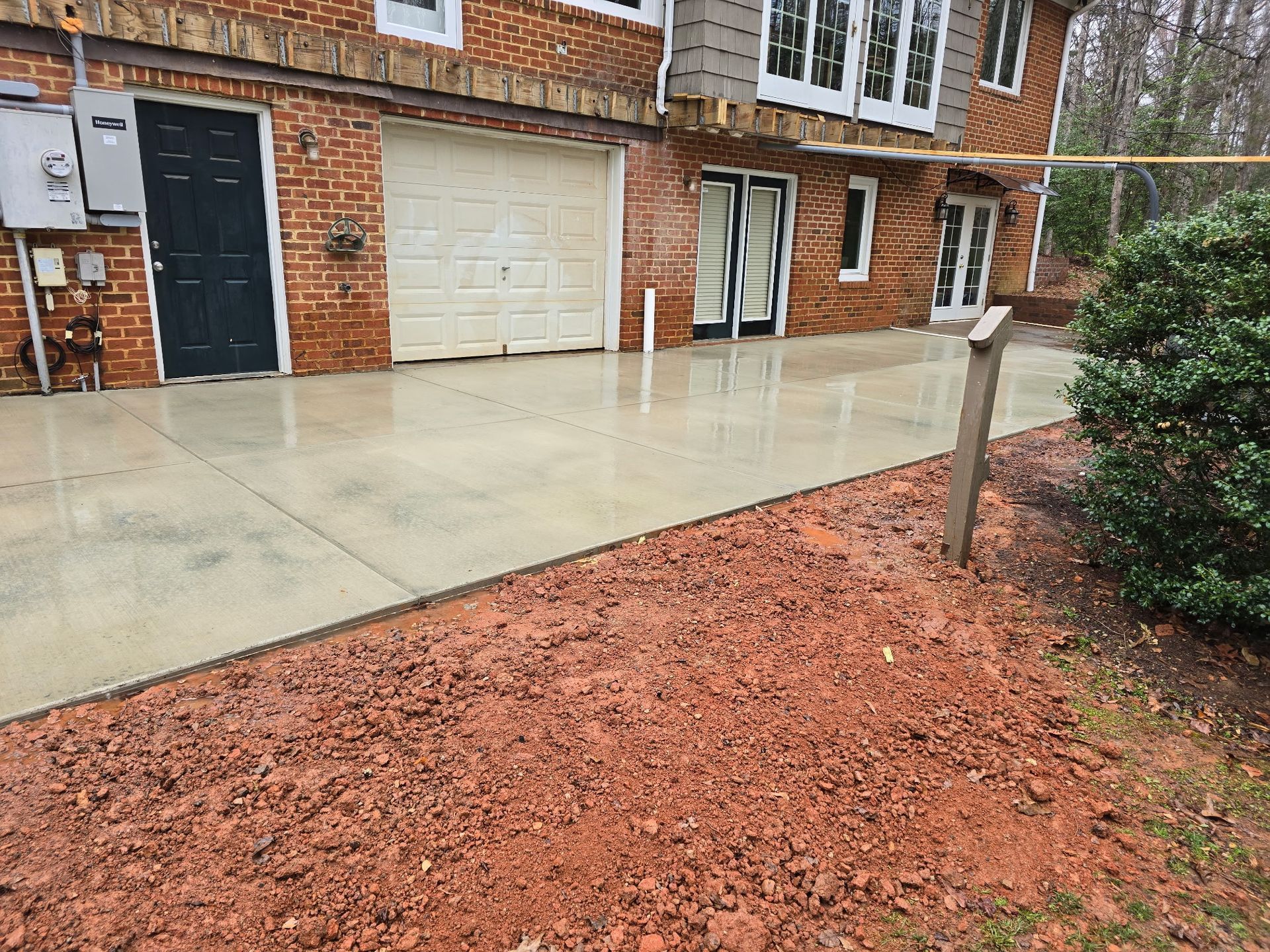 Brick townhouse driveway with a wet concrete patio and red gravel landscaping
