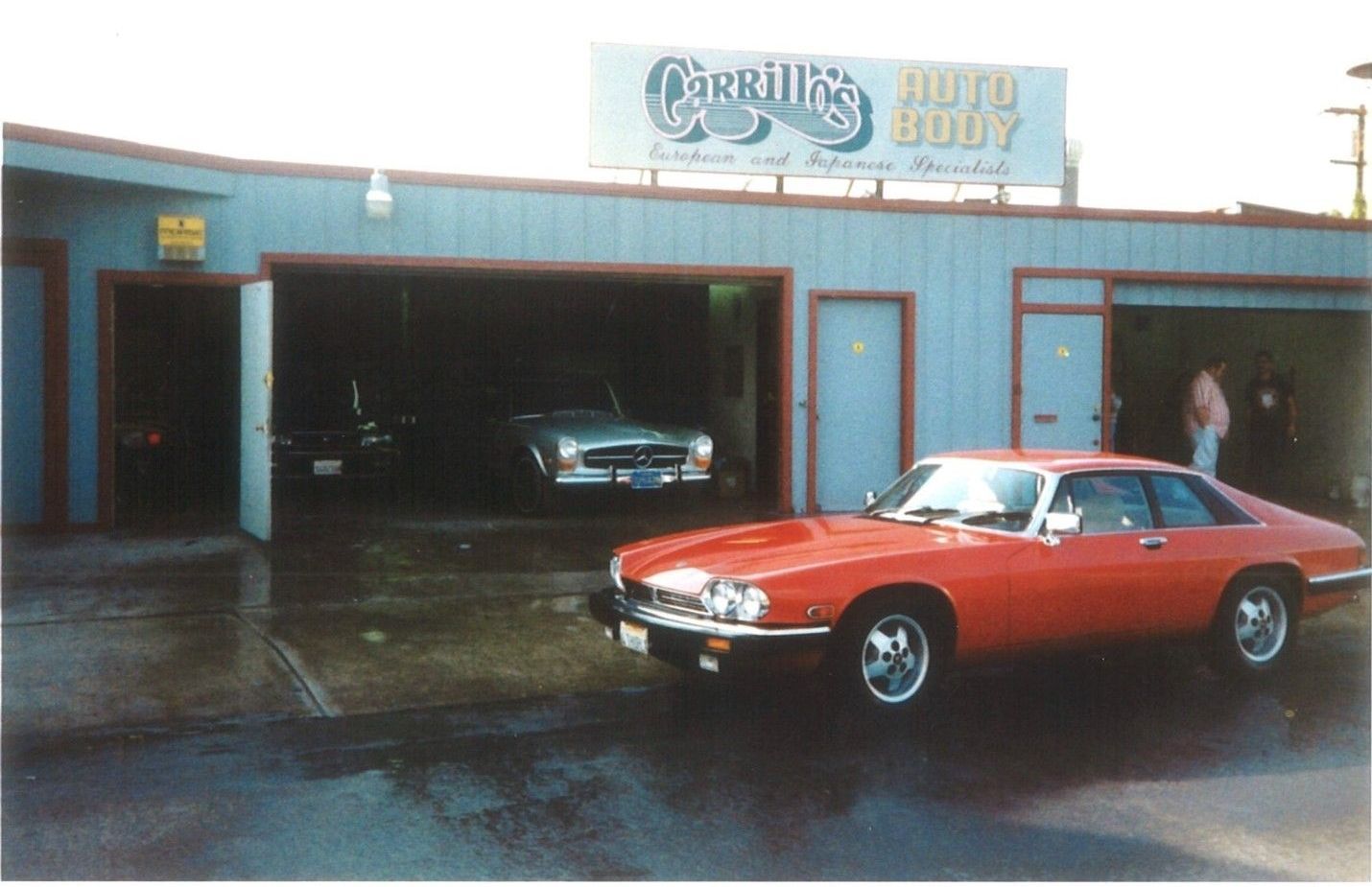 A red car is parked in front of a building that says cadillac auto body
