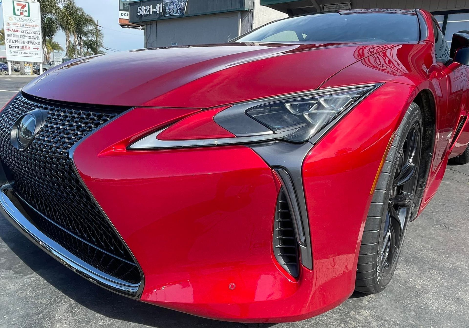 A red lexus lc 500 is parked in front of a building.