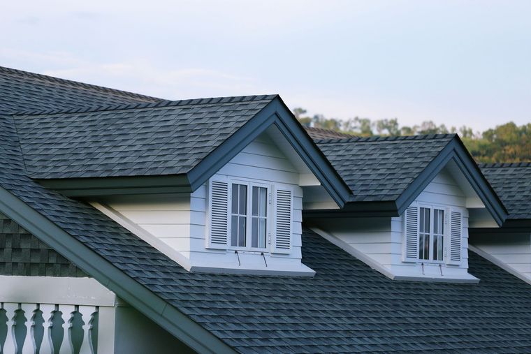 Gray shingled roof with white dormers, blue trim, and small windows.