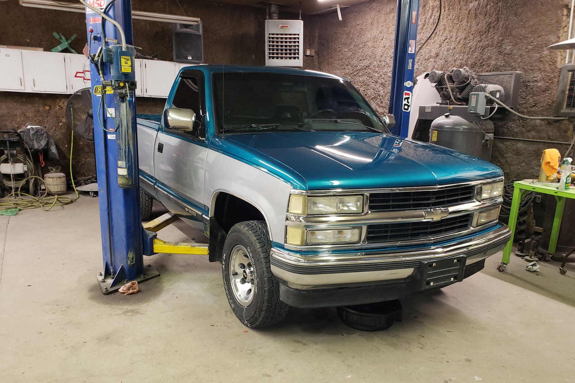 a blue and white truck is parked on a lift in a garage