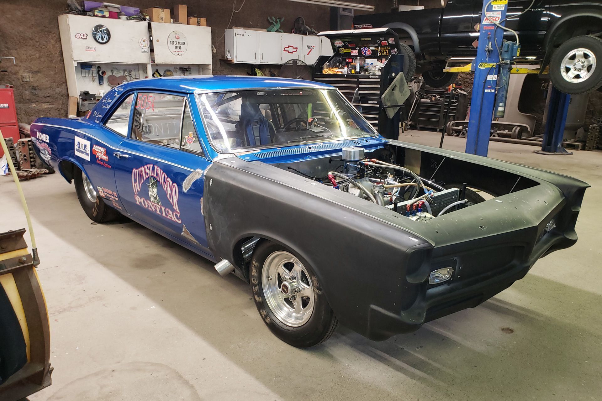 a blue car with the hood open is parked in a garage