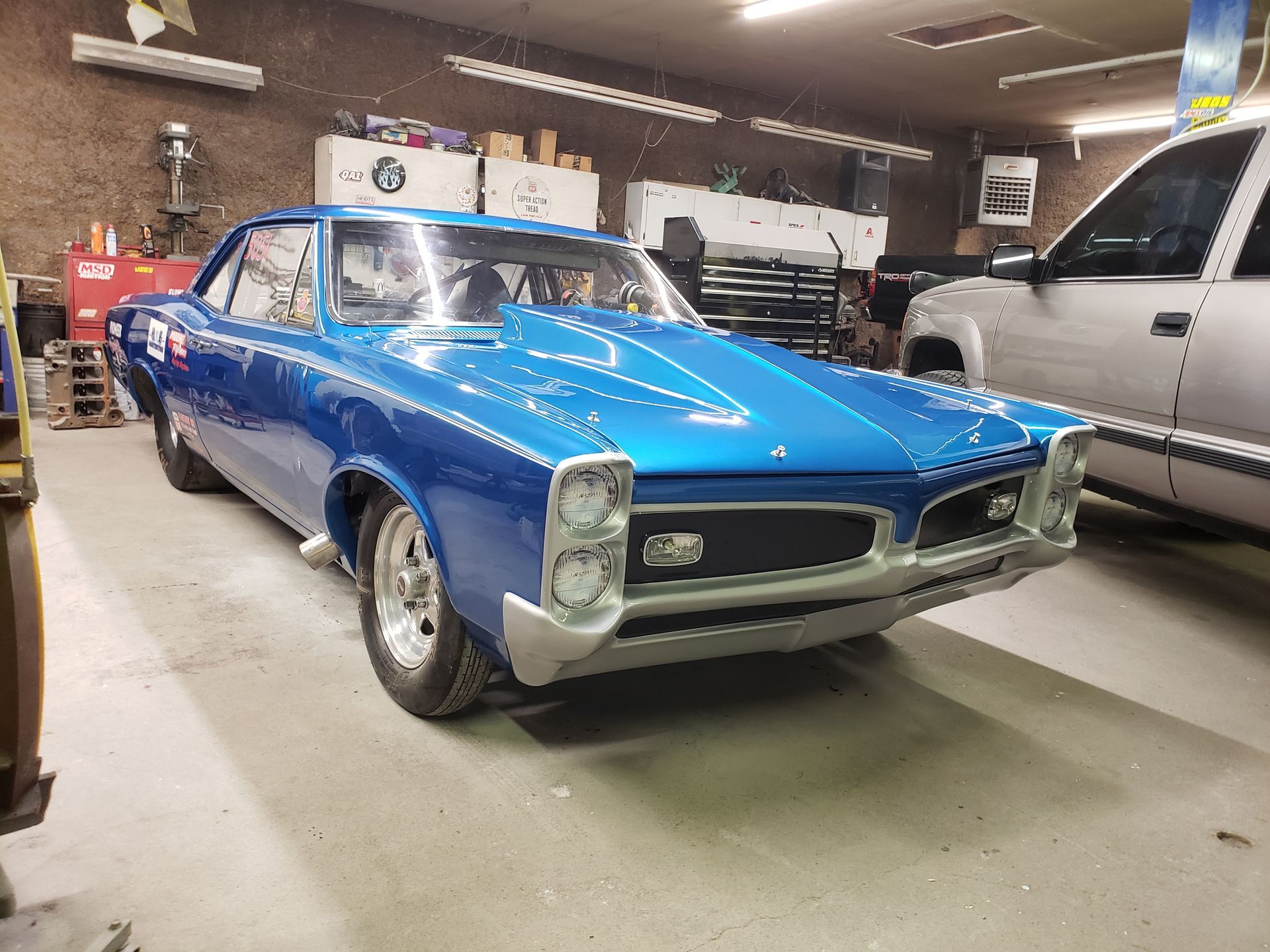 a blue car is parked in a garage next to a silver truck