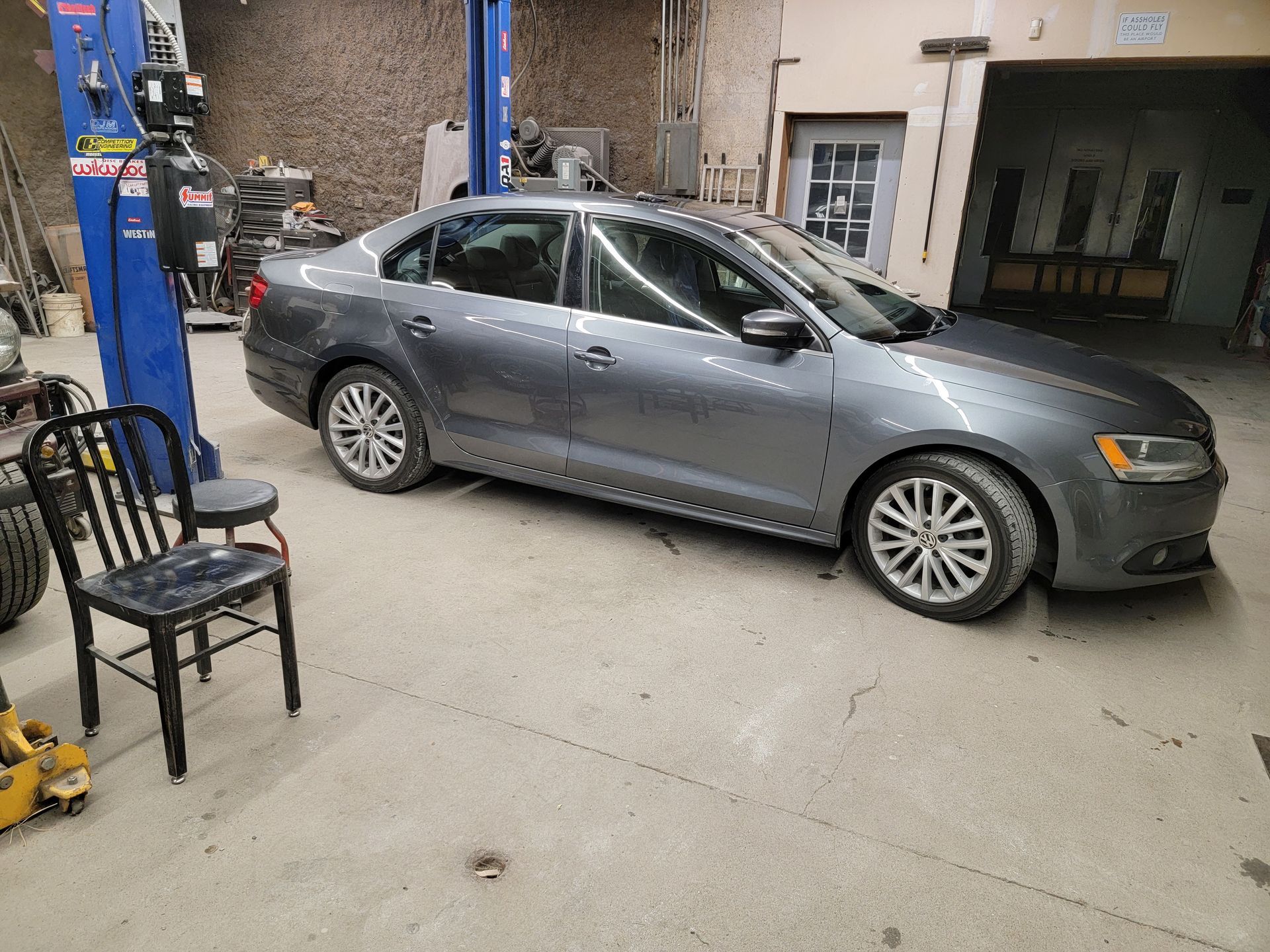 a gray car is parked in a garage next to a chair