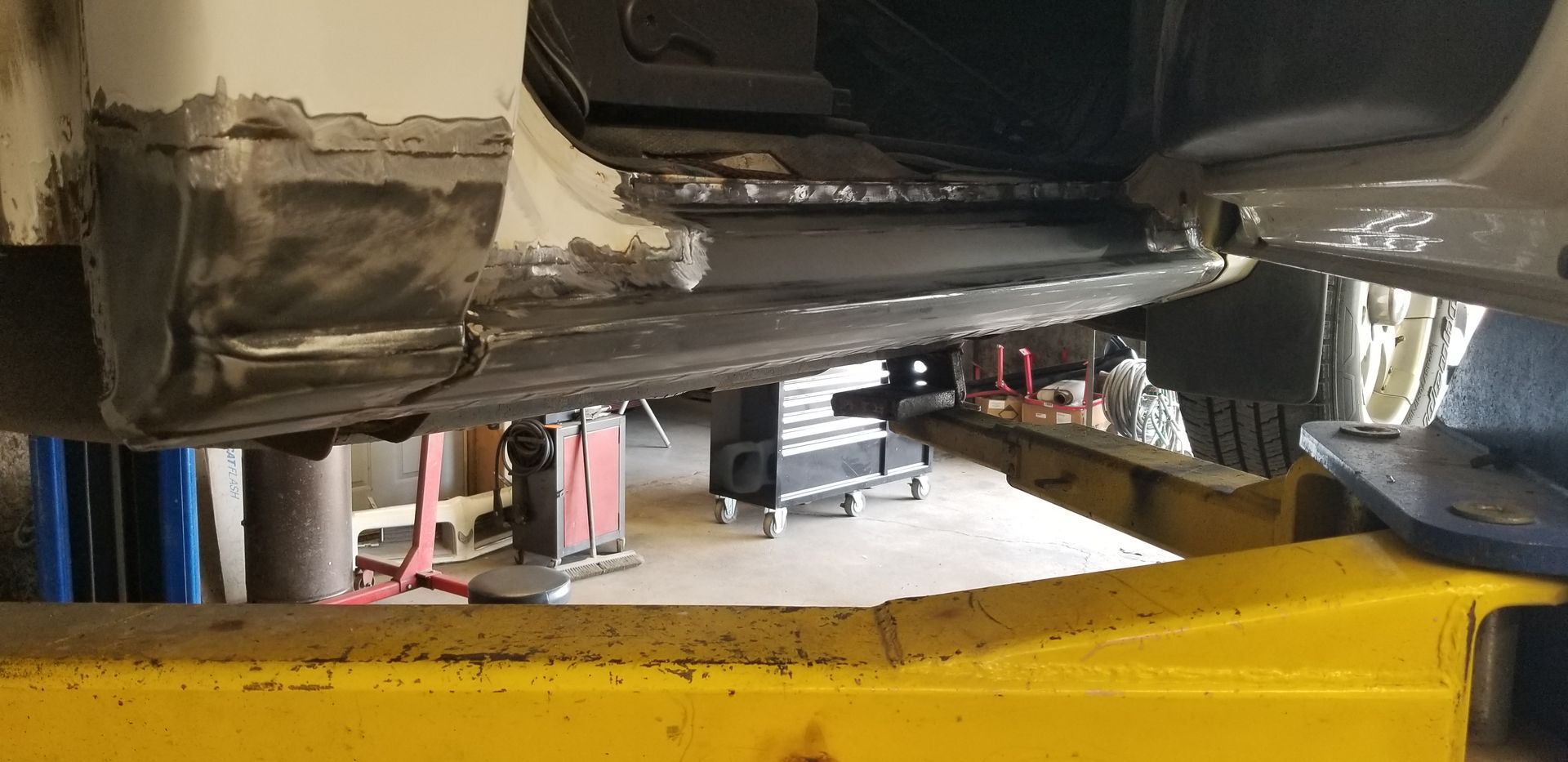 a car is sitting on top of a yellow lift in a garage