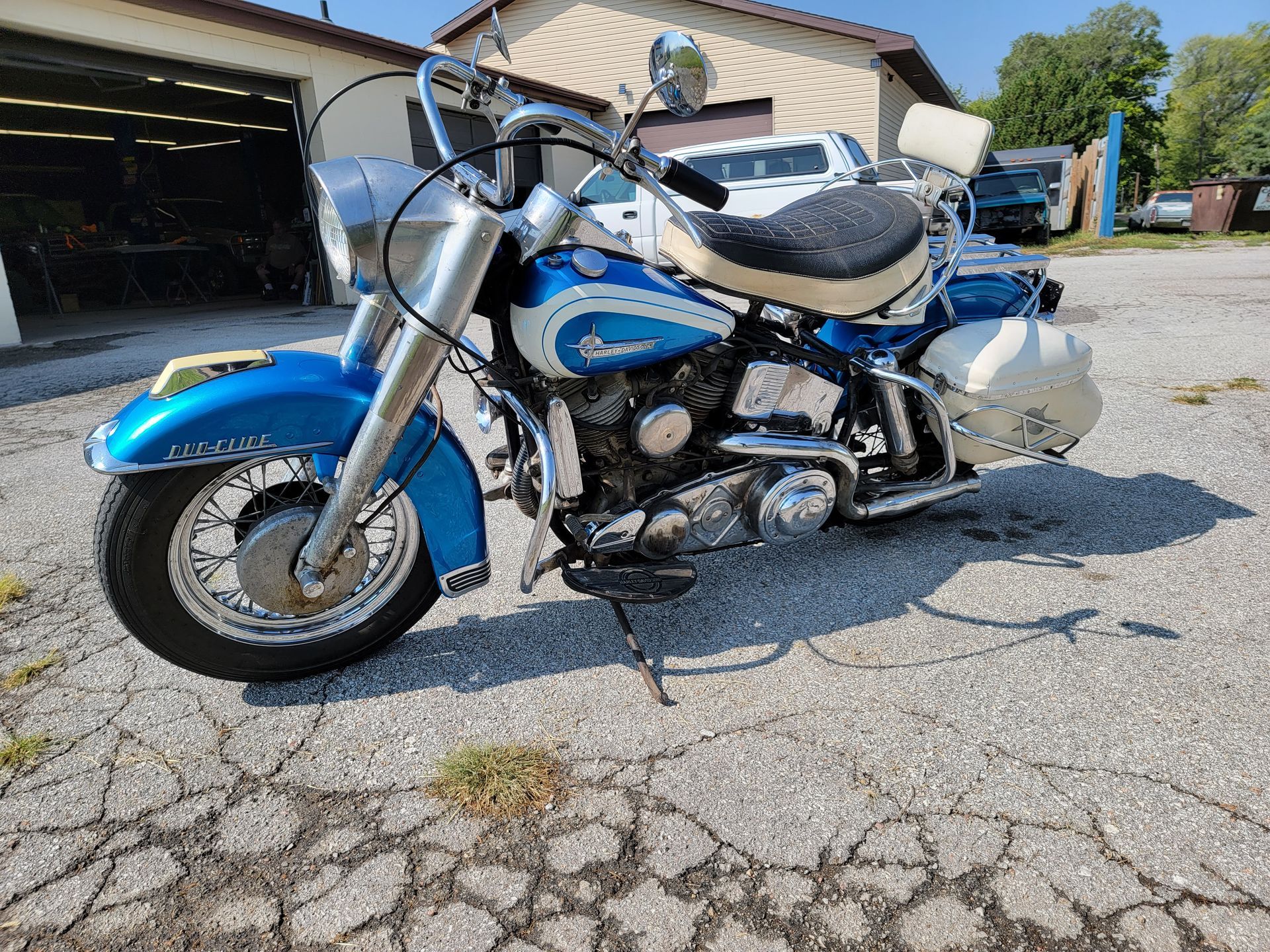 a blue and white motorcycle is parked in front of a garage