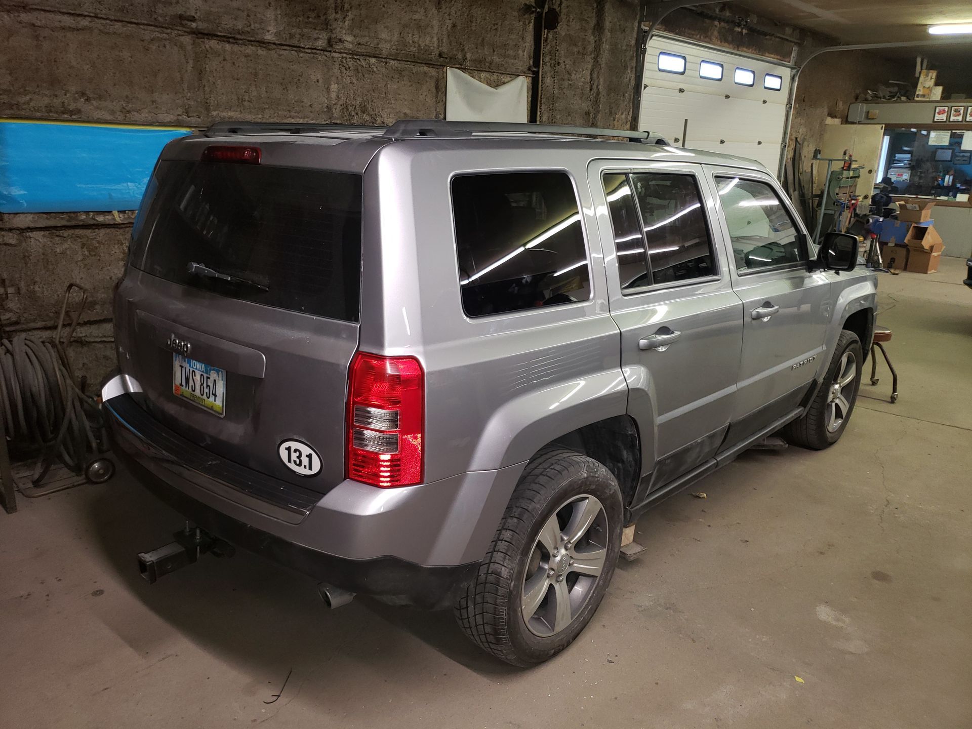 a gray jeep is parked in a garage next to a garage door