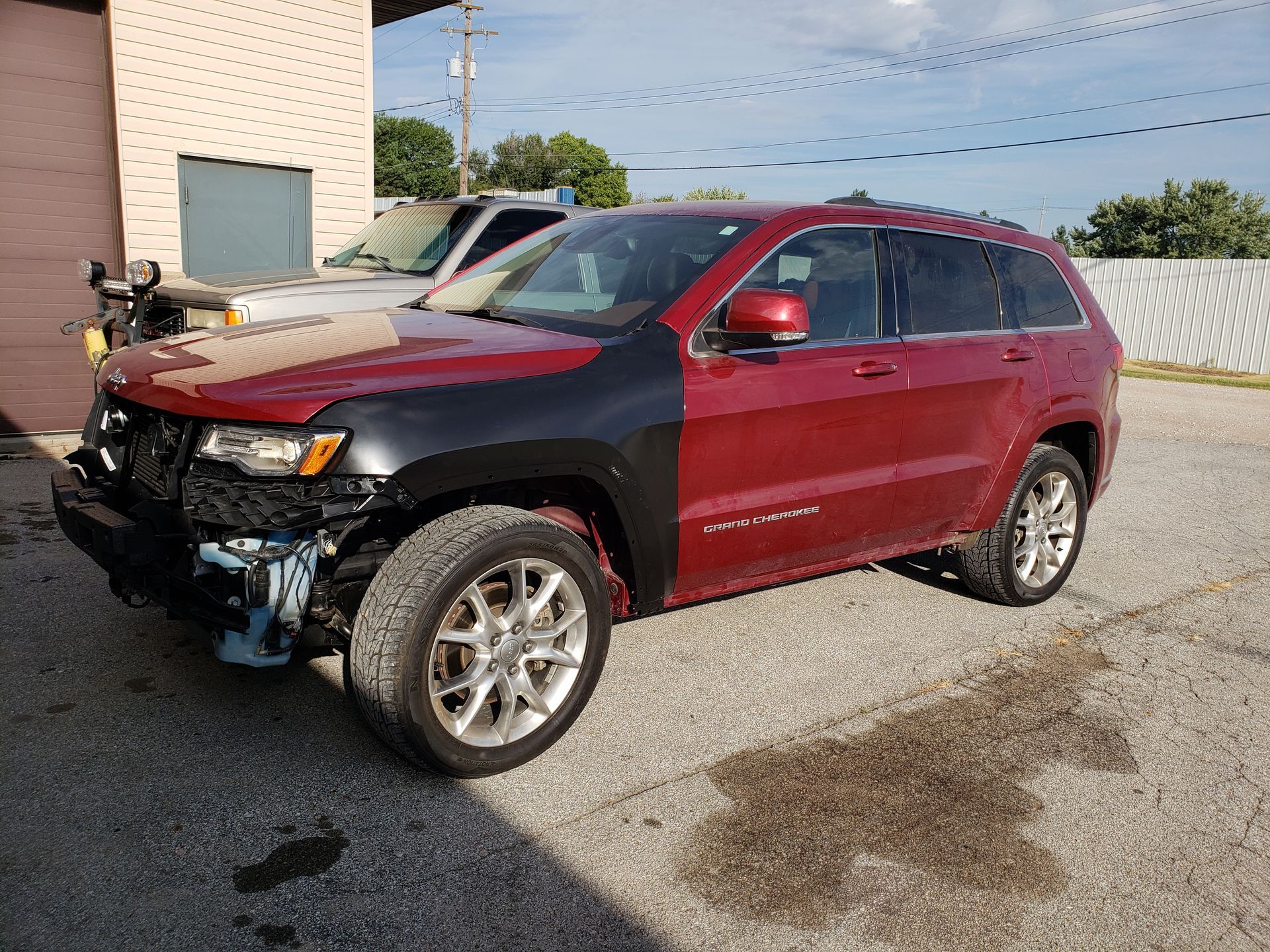 a red jeep is parked in a parking lot next to a building
