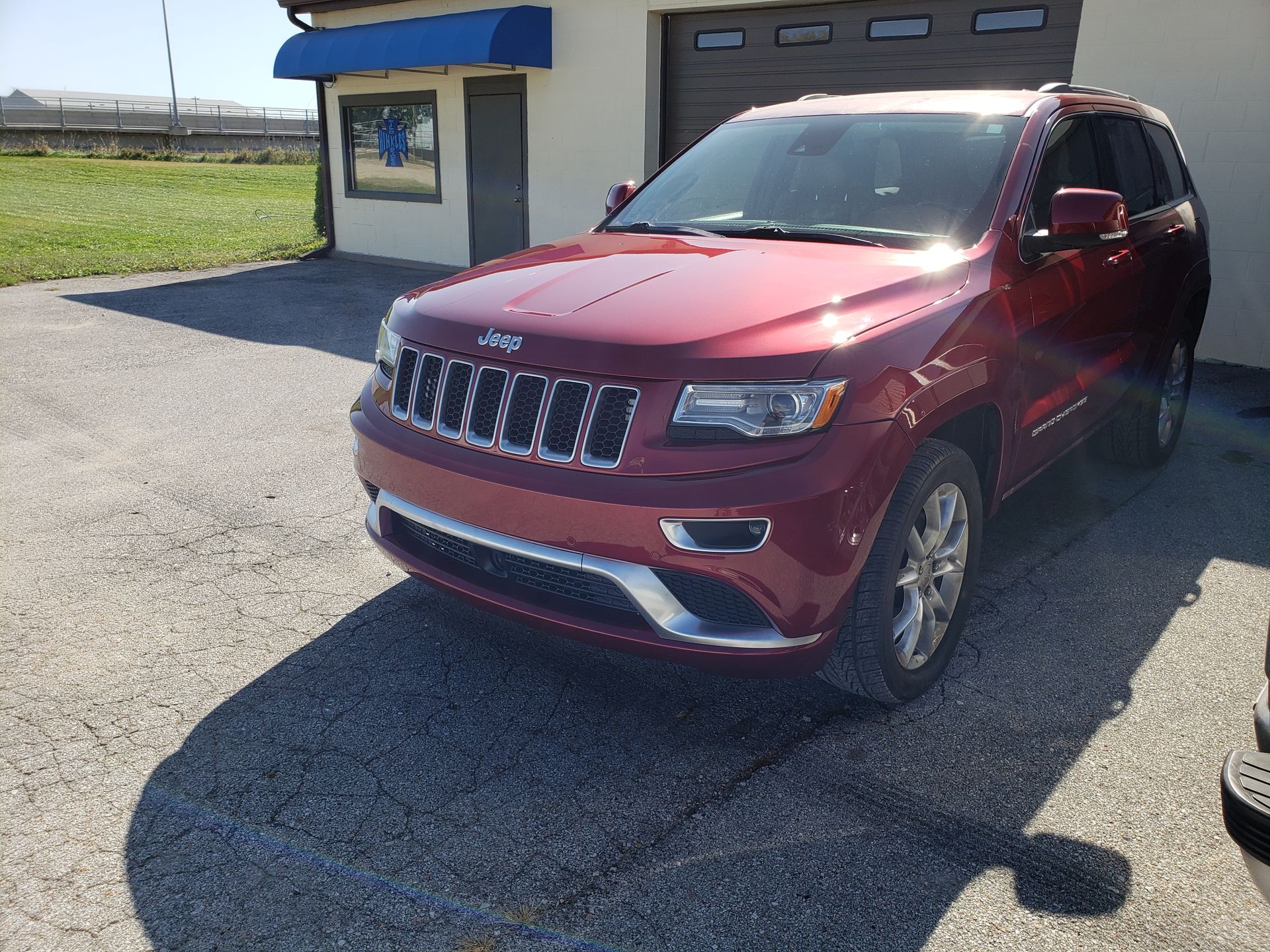 a red jeep grand cherokee is parked in front of a garage