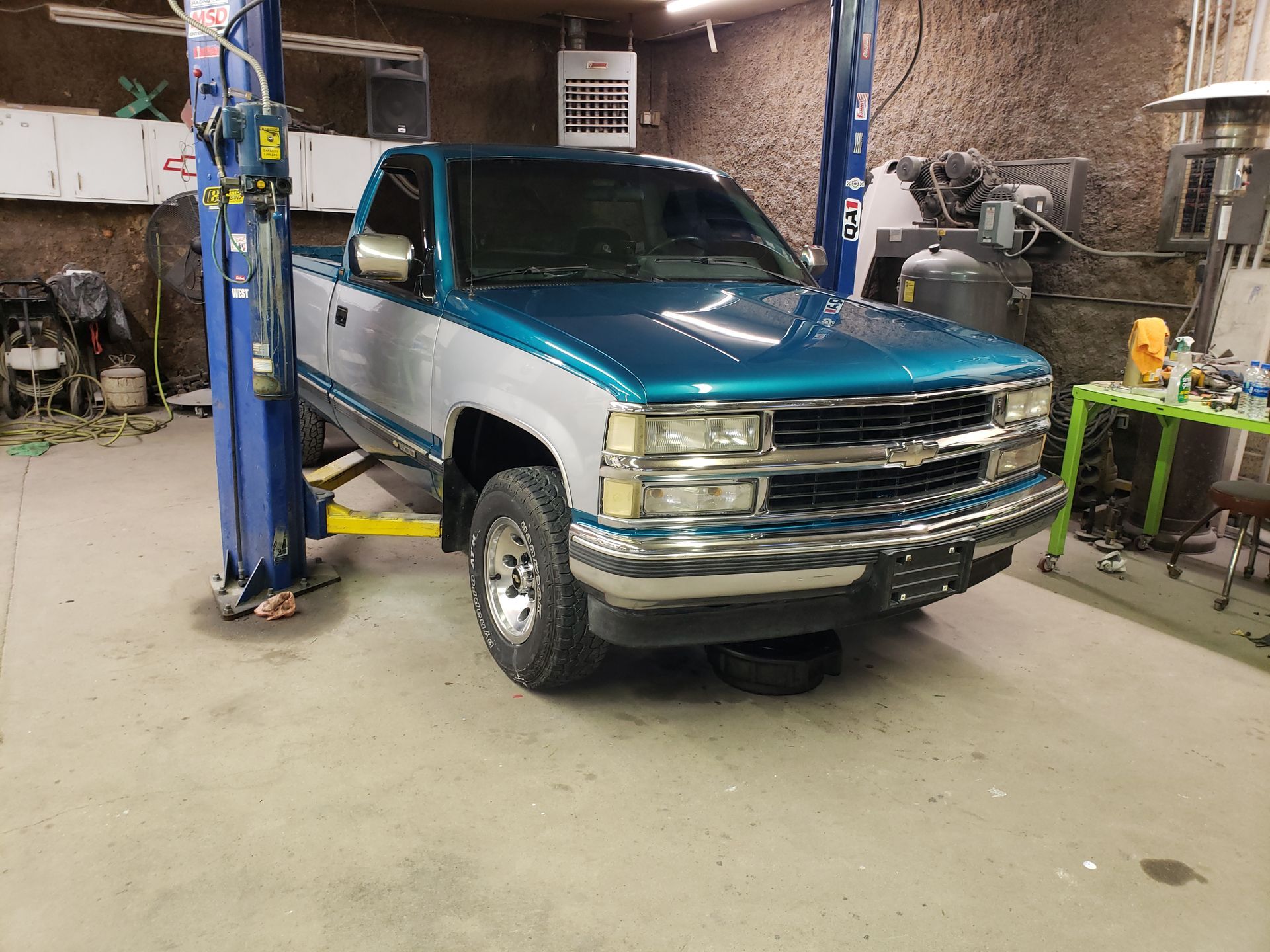 a blue and white truck is parked on a lift in a garage