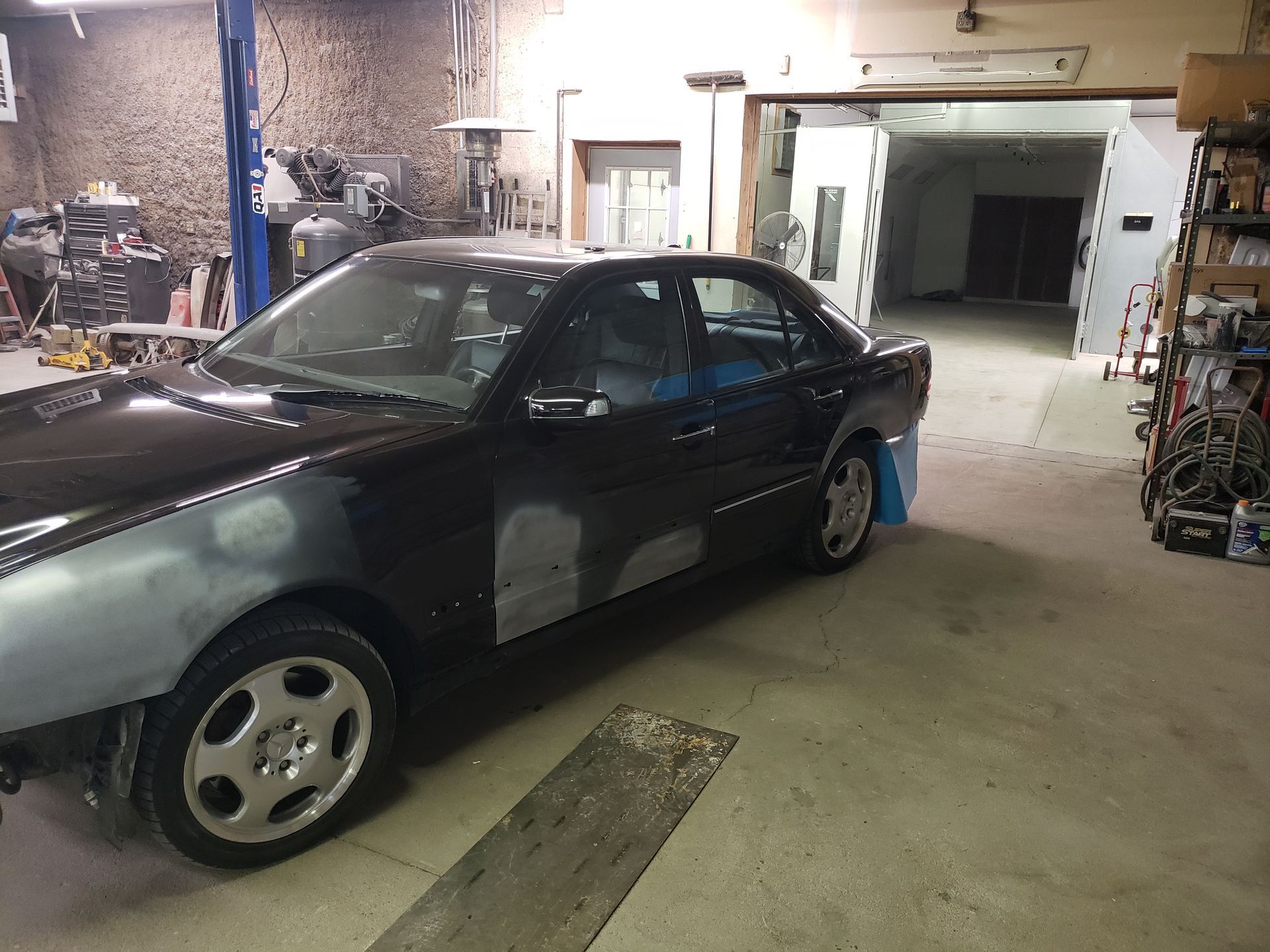 a black car is sitting in a garage being painted