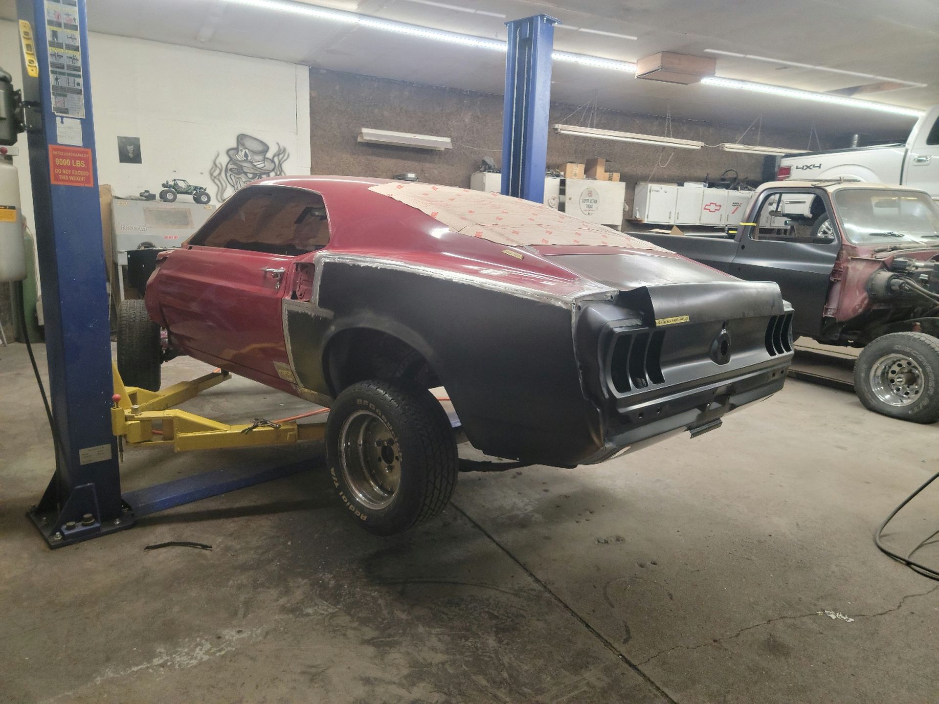 a red mustang is sitting on a lift in a garage