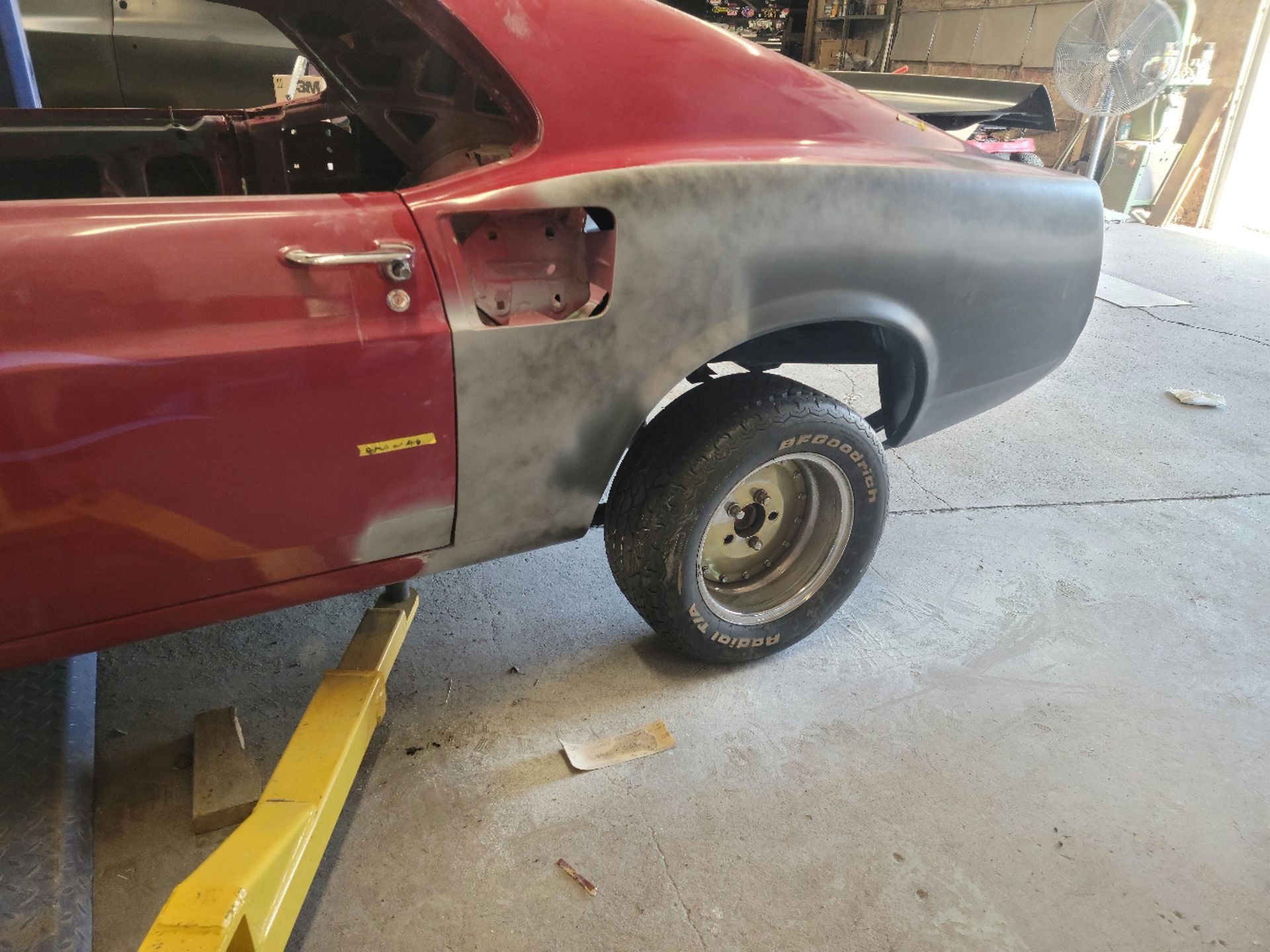 a red car is sitting on a yellow lift in a garage