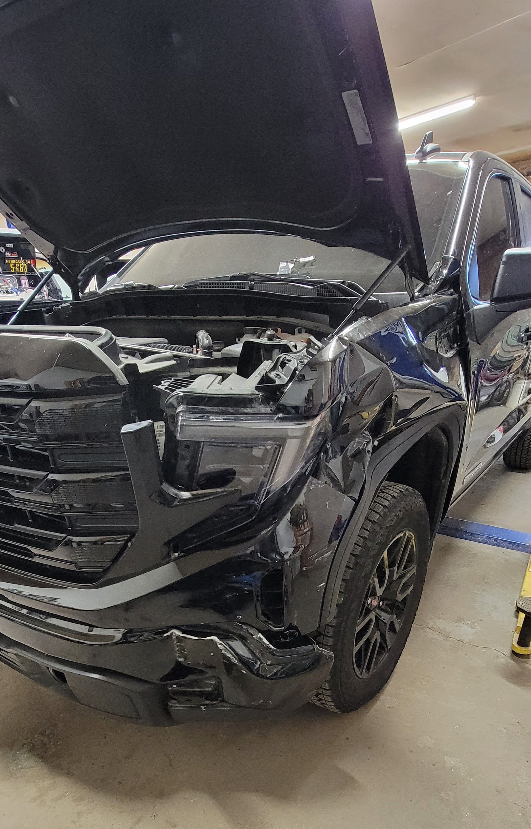 a black truck with the hood up is parked in a garage
