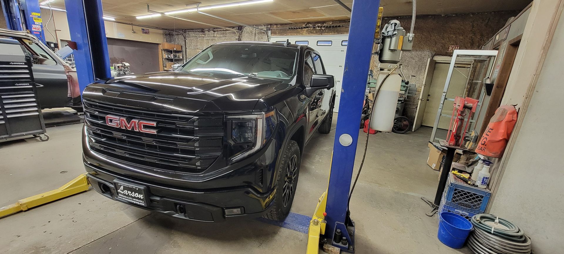 a black gmc truck is parked on a lift in a garage