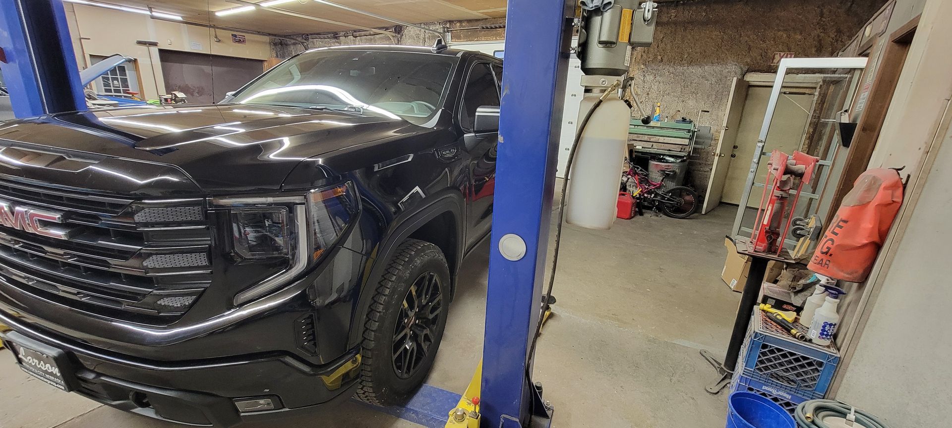 a black truck is sitting on top of a blue lift in a garage
