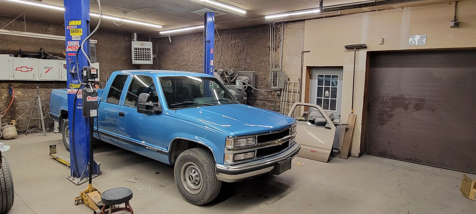 a blue truck is parked on a lift in a garage