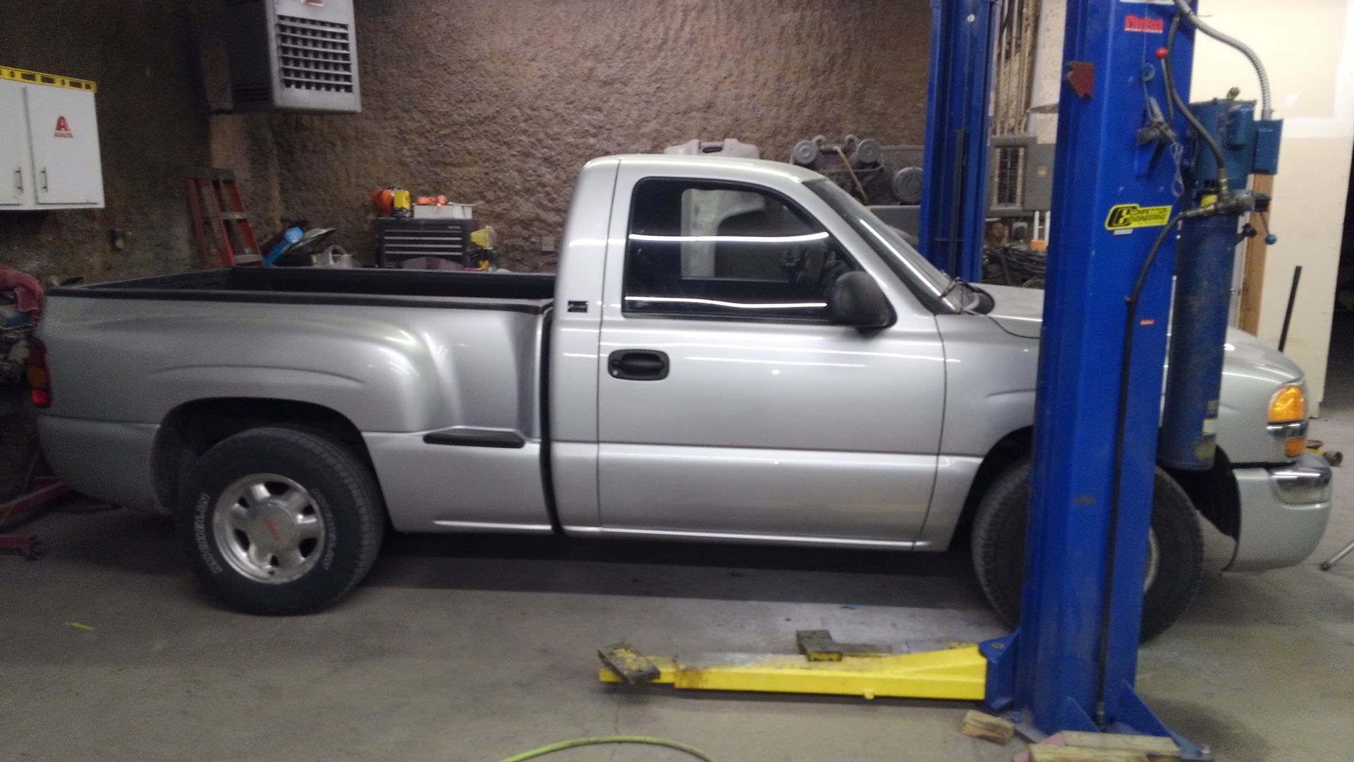 a silver truck is parked on a blue lift in a garage