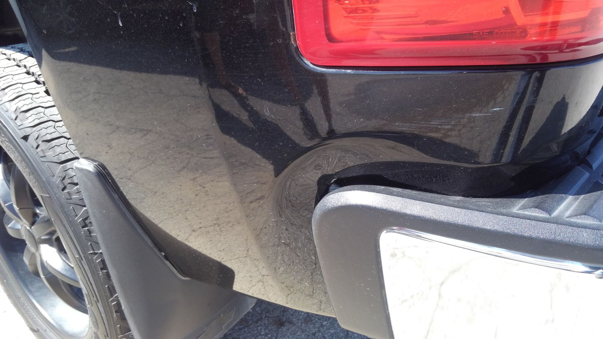 a close up of a black truck 's bumper and tail light