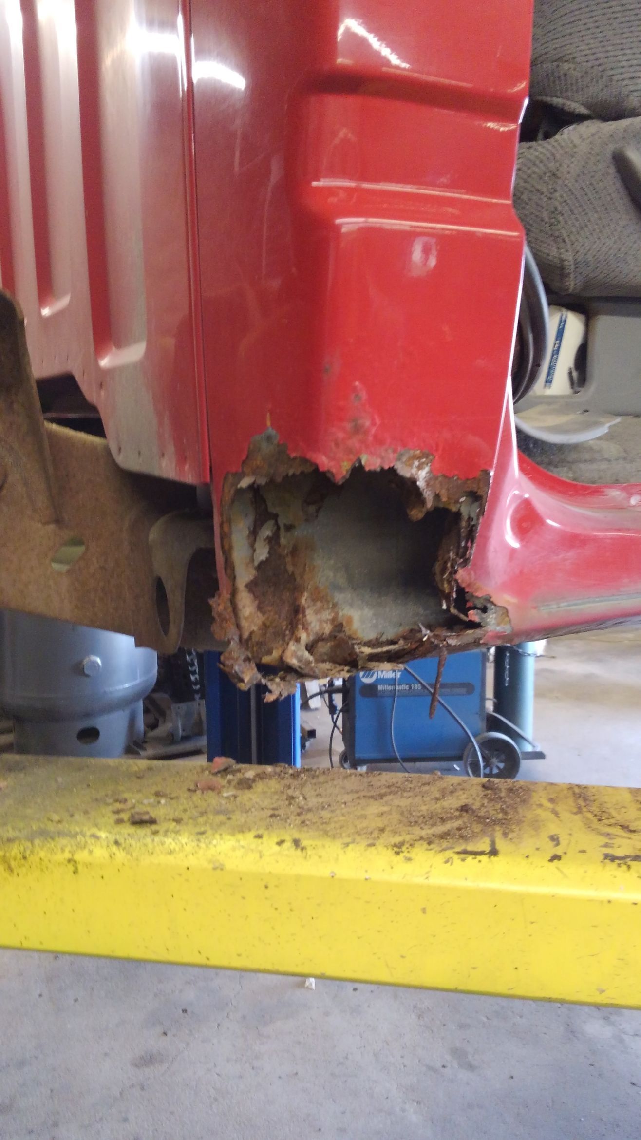 a red car is sitting on a yellow lift in a garage