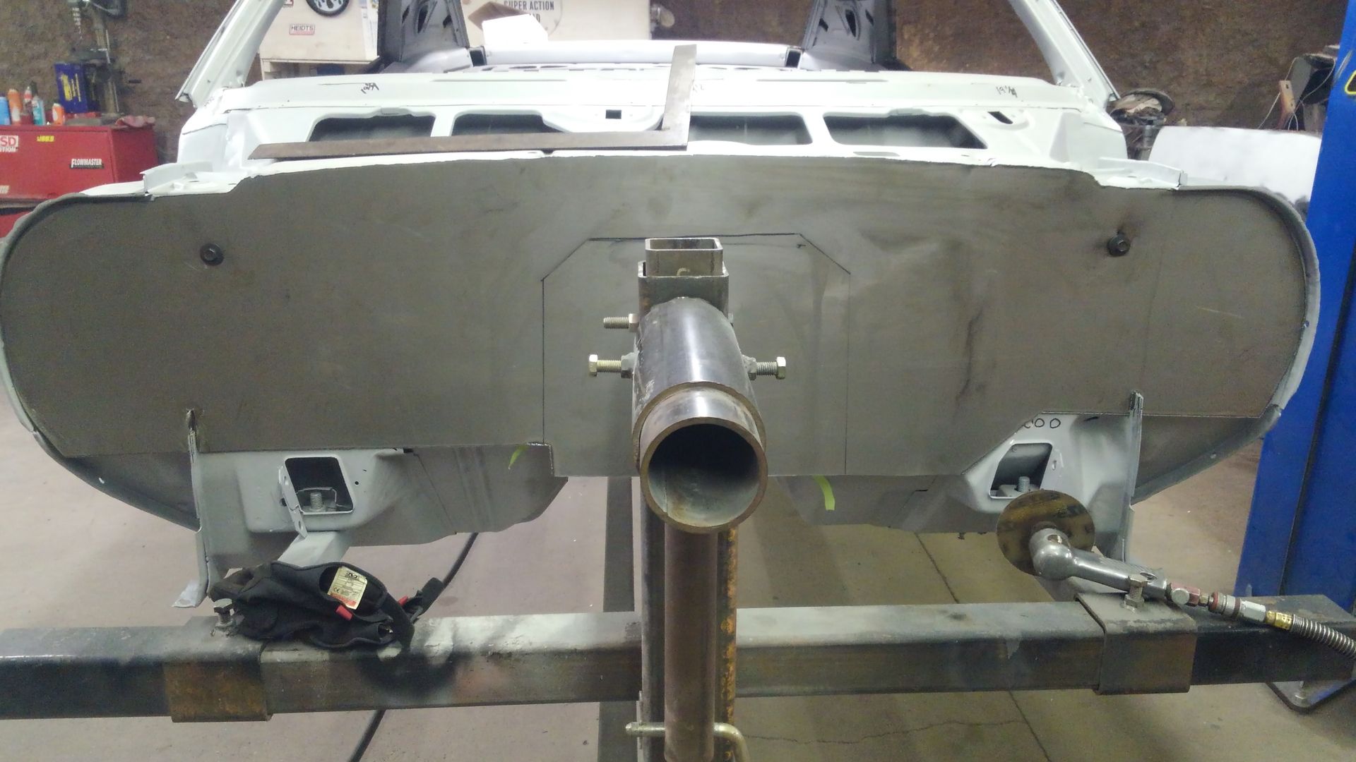 a white car is sitting on a metal stand in a garage