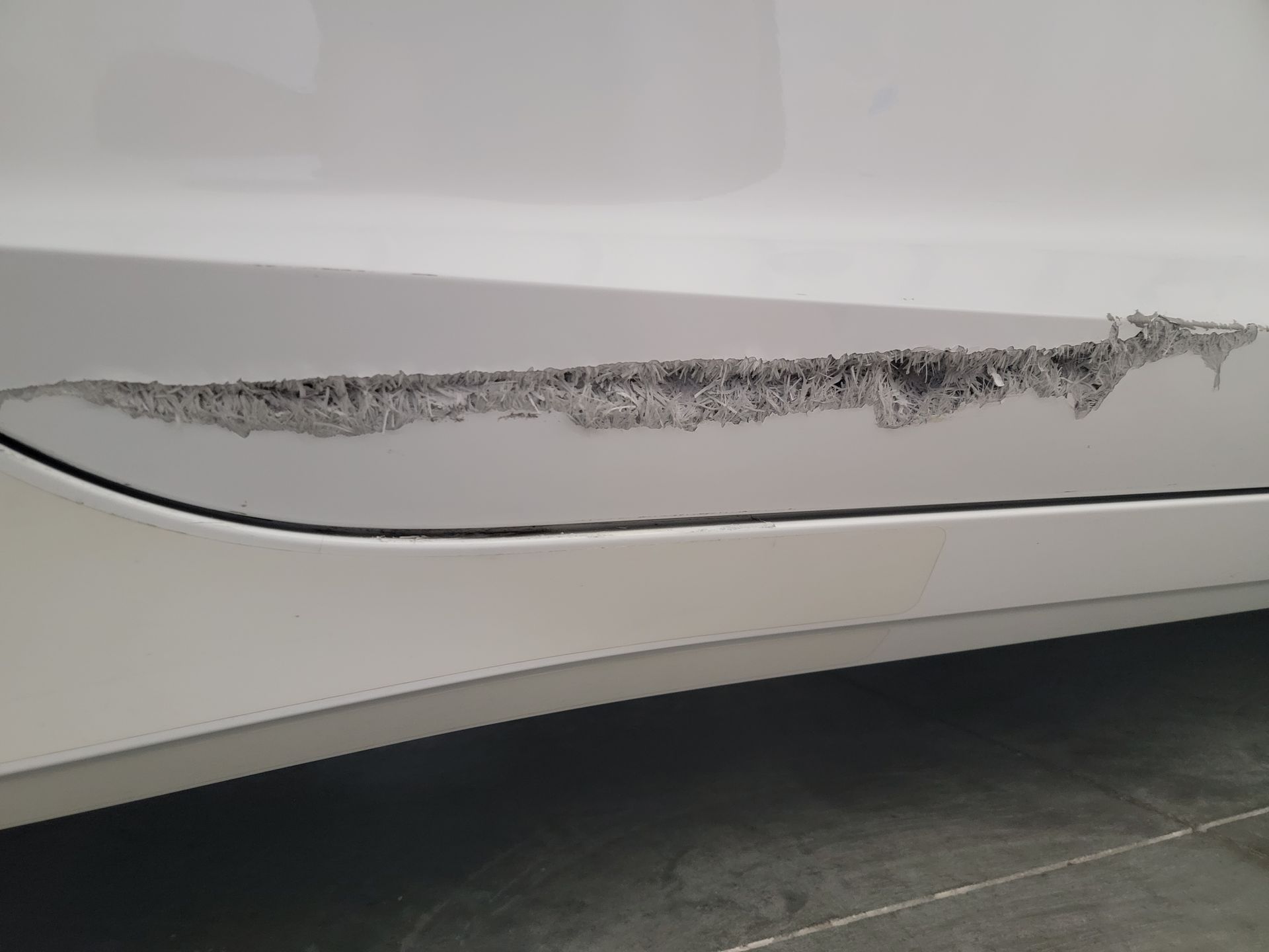 a white car with a scratch on the side of it