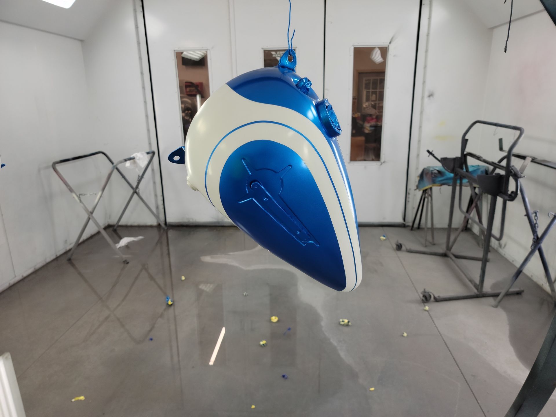 a blue and white motorcycle is being painted in a paint booth