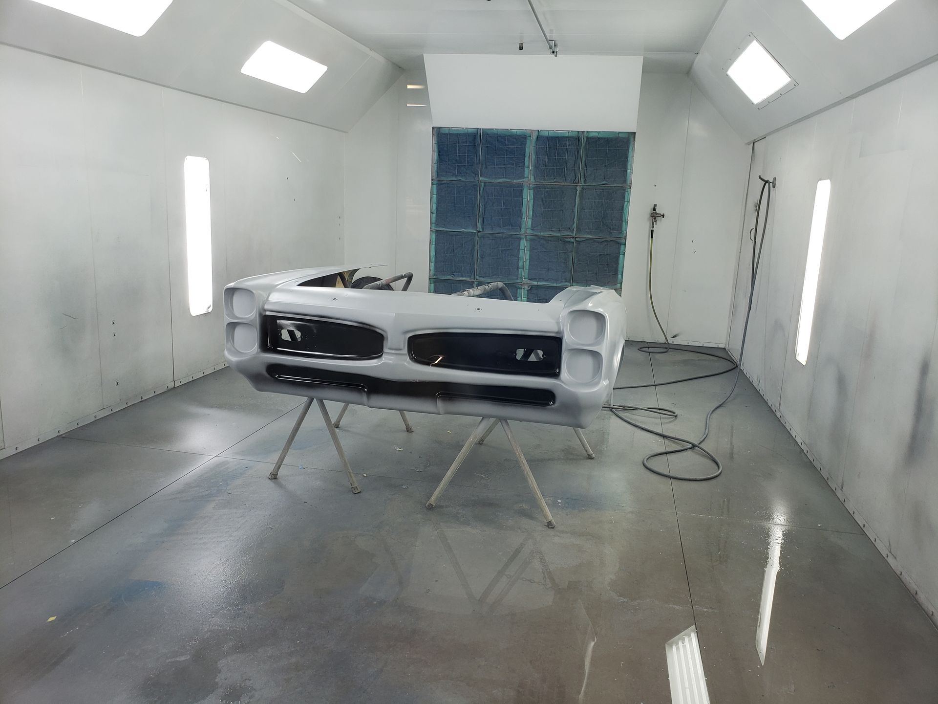 a white car is being painted in a paint booth