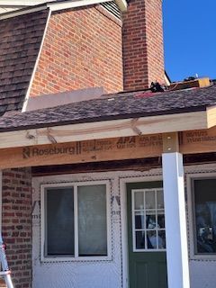 Construction site, building exterior. A roof extension is being built, next to brick chimney.