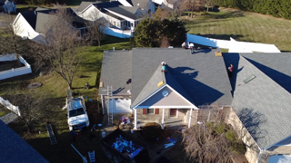 Roofers working on a house roof; several houses in a suburban neighborhood.