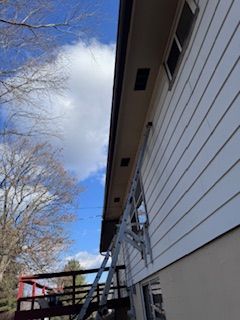 Ladder against a house; blue sky with clouds.