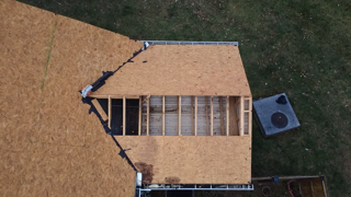 Overhead view of a roof under construction. Wooden frame and OSB sheathing are visible.