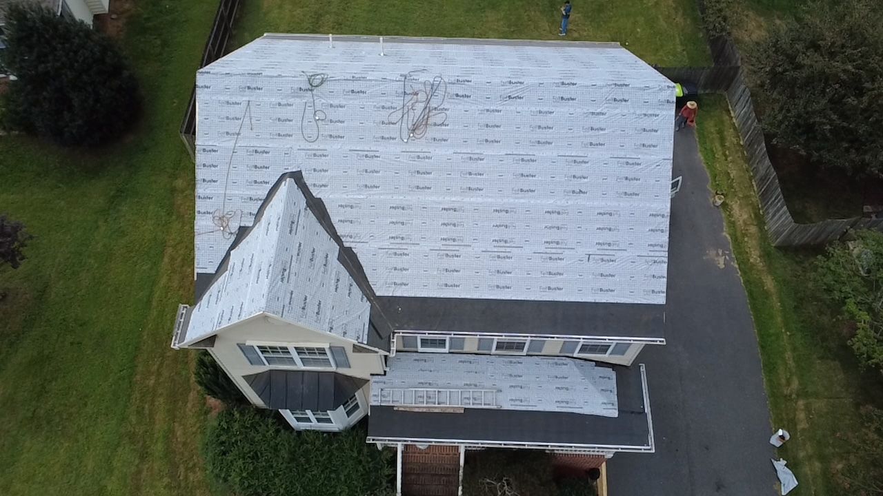 Overhead view of a house with a gray roof, surrounded by green grass and a driveway.