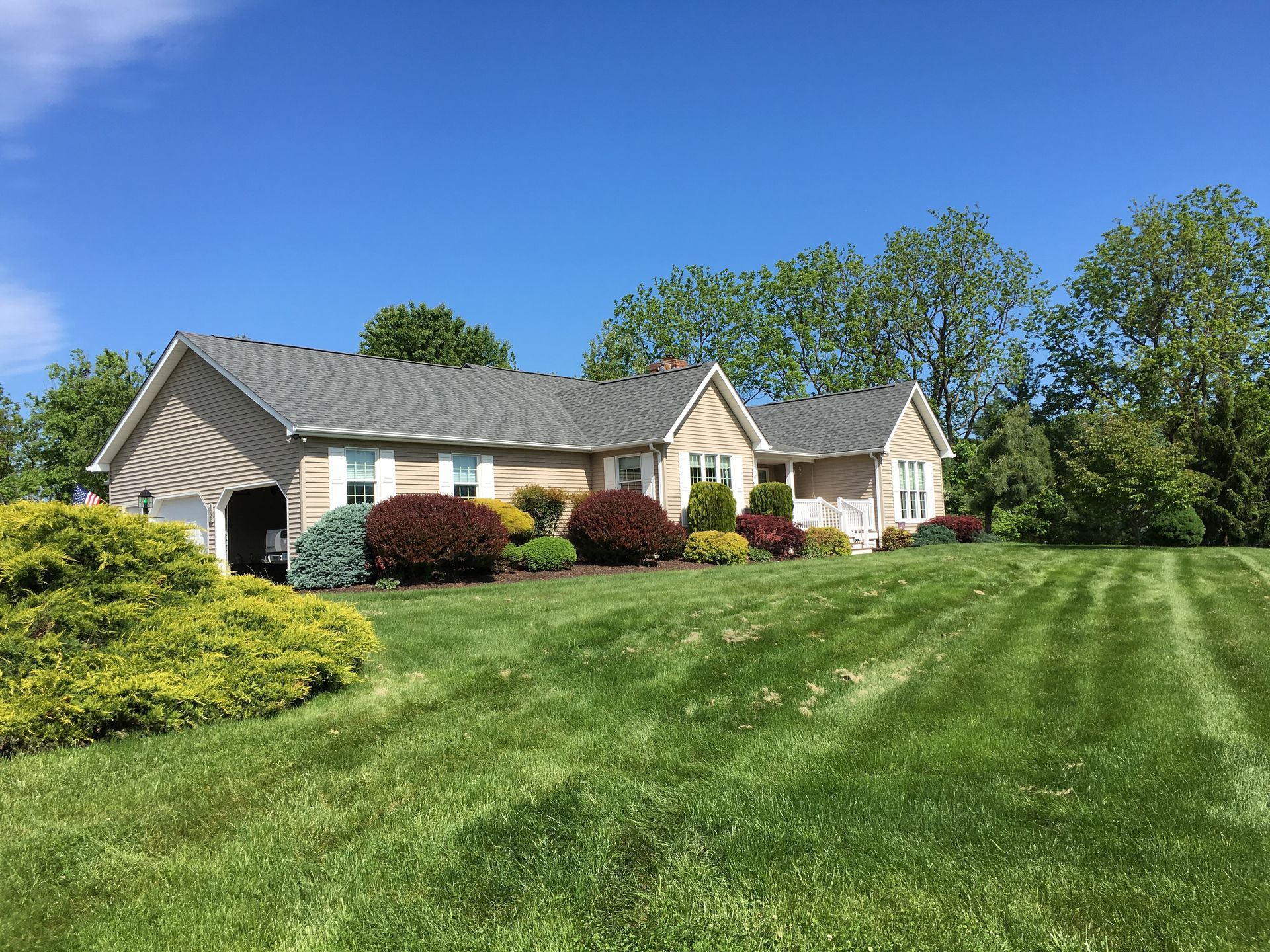 Ranch-style house with manicured lawn and landscaping on a sunny day.