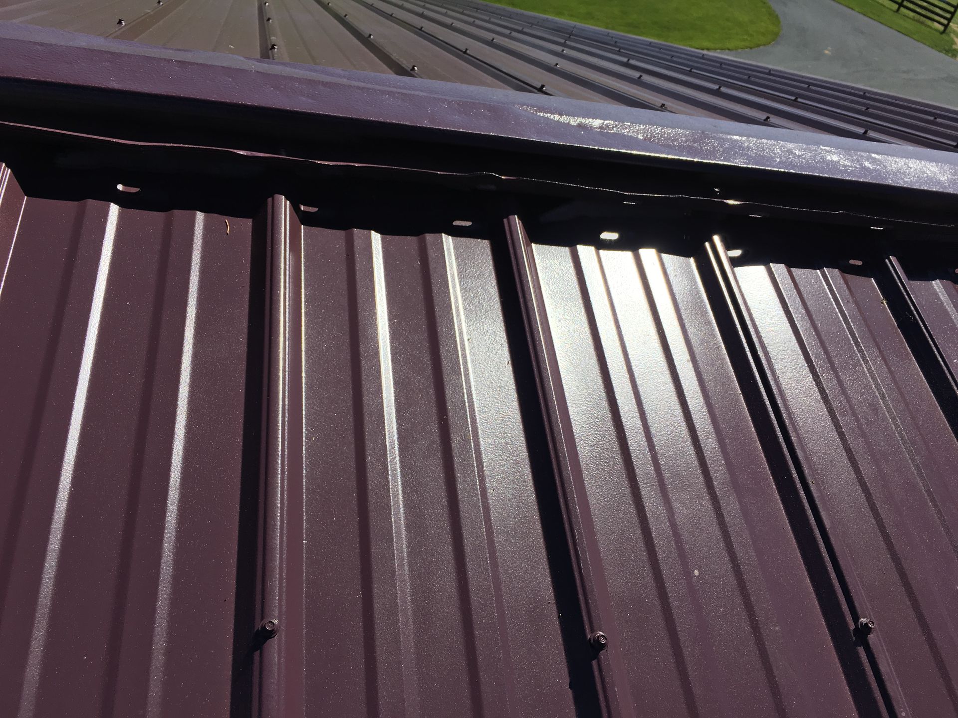 Close-up of a burgundy metal roof with vertical ridges.